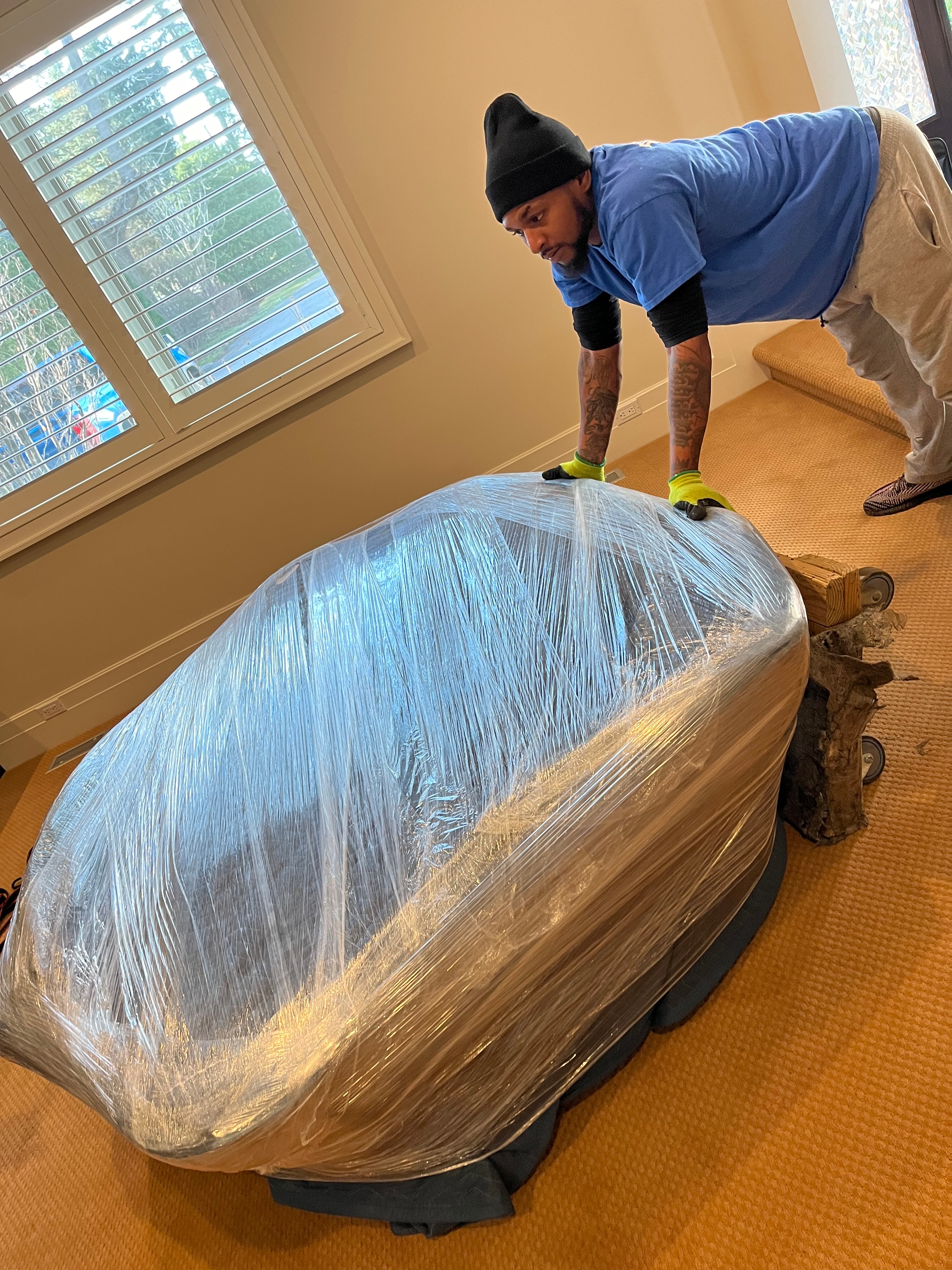 Mover wrapping furniture in plastic stretch wrap for protection